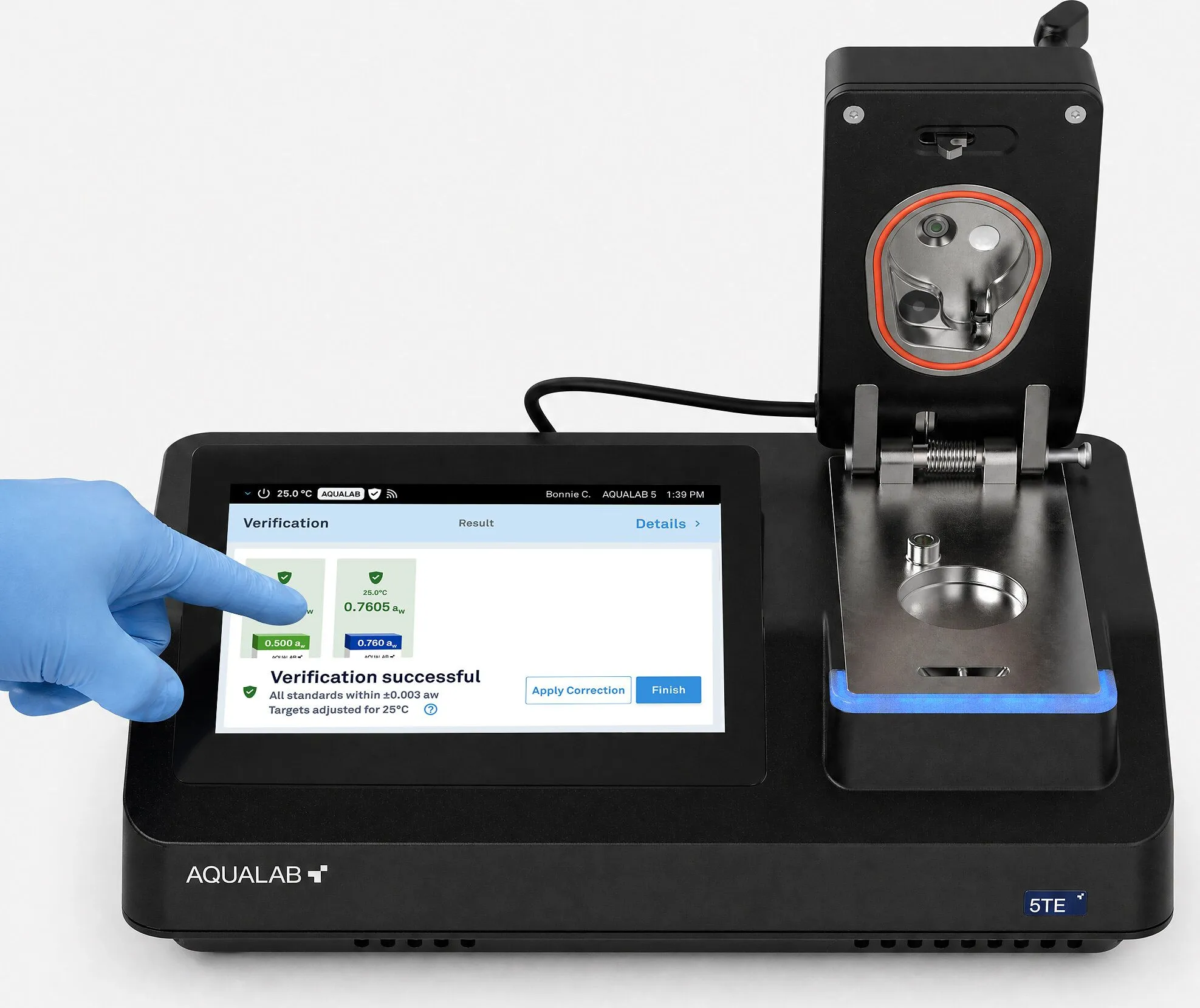 A gloved hand operates an Aqualab 5TE moisture analyser touchscreen.