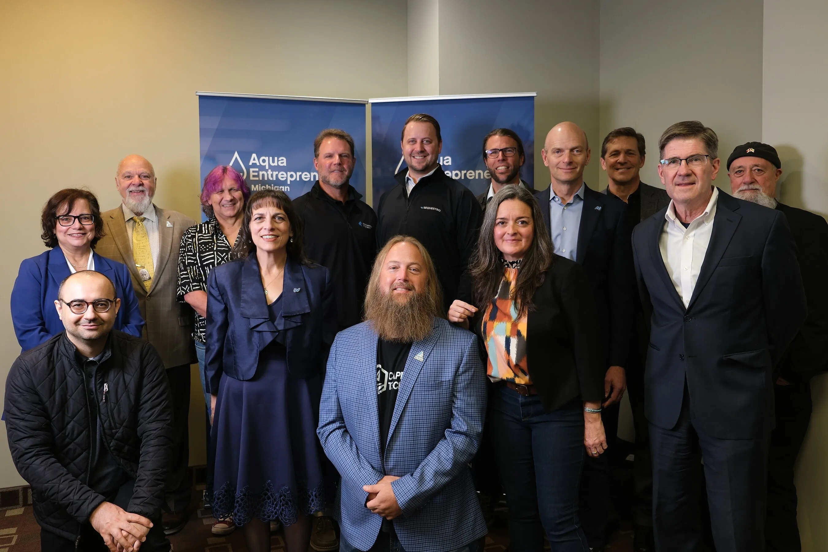 Group photo in front of AquaEntrepreneur Michigan banners.